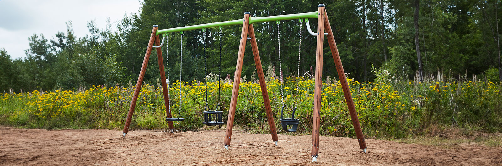 Large wooden swing frame with different swing seat attachments at a playground.